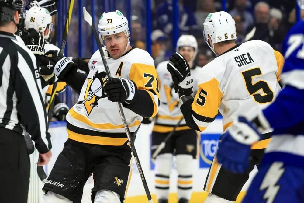 Pittsburgh Penguins center Evgeni Malkin fist-bumps teammates on the ice during an NHL game.